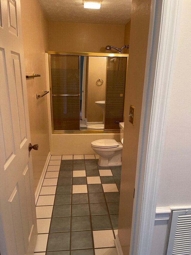 1412 Secreretariat Dr, Morristown, TN 37814 - bathroom featuring tile patterned floors, combined bath / shower with glass door, a textured ceiling, and toilet