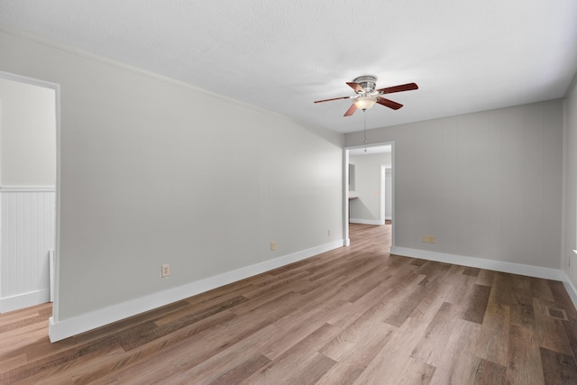 spare room featuring baseboards, visible vents, a ceiling fan, wood finished floors, and a textured ceiling