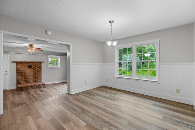 unfurnished dining area featuring ceiling fan, a textured ceiling, visible vents, and wood finished floors