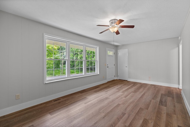 empty room featuring baseboards, visible vents, ceiling fan, wood finished floors, and a textured ceiling