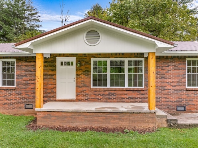 view of front of house featuring crawl space, brick siding, and metal roof