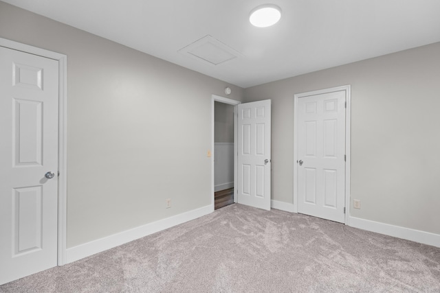 unfurnished bedroom with carpet, attic access, and baseboards