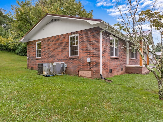 view of side of home featuring crawl space, brick siding, a yard, and central AC