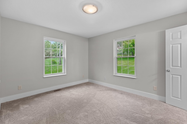 spare room with carpet floors, a healthy amount of sunlight, and visible vents