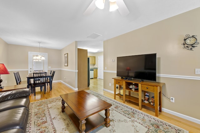 living room featuring ceiling fan with notable chandelier and light hardwood / wood-style floors