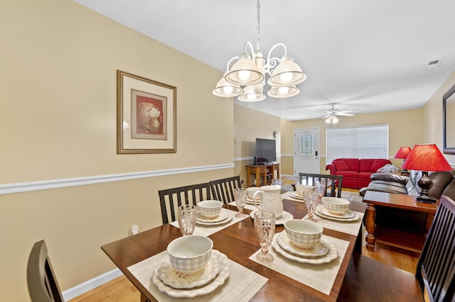 dining space featuring ceiling fan with notable chandelier and wood-type flooring