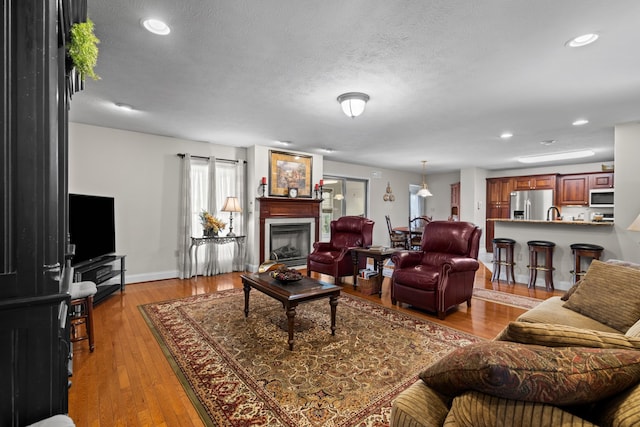 5704 Long Creek Rd, Morristown, TN 37813 - living area featuring a glass covered fireplace, light wood-style flooring, a textured ceiling, and recessed lighting