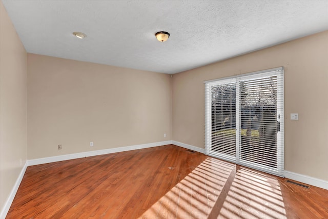 spare room featuring hardwood / wood-style floors and a textured ceiling