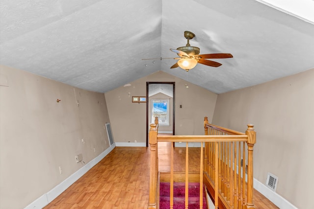 bonus room with ceiling fan, lofted ceiling, light hardwood / wood-style floors, and a textured ceiling