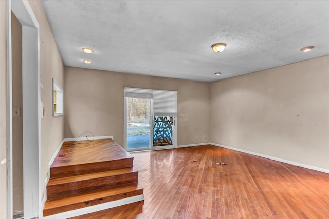 spare room featuring hardwood / wood-style flooring and a textured ceiling