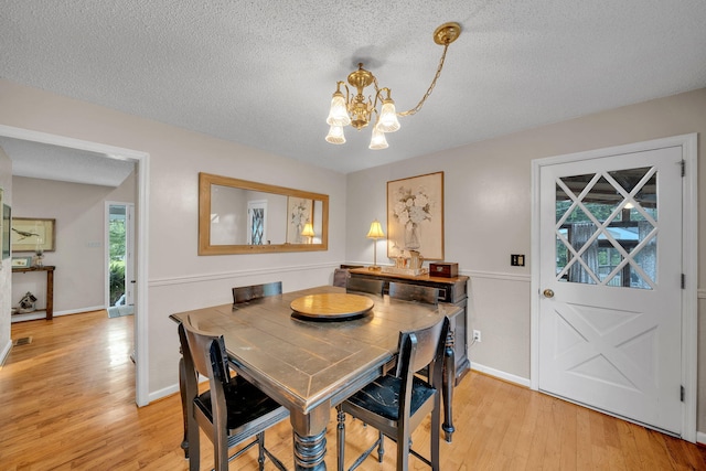 1216 Winding Dr, Sevierville, TN 37876 - dining area with light wood-style floors, a chandelier, a textured ceiling, and baseboards