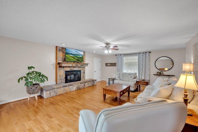 1216 Winding Dr, Sevierville, TN 37876 - living room featuring a ceiling fan, a stone fireplace, a textured ceiling, wood finished floors, and baseboards