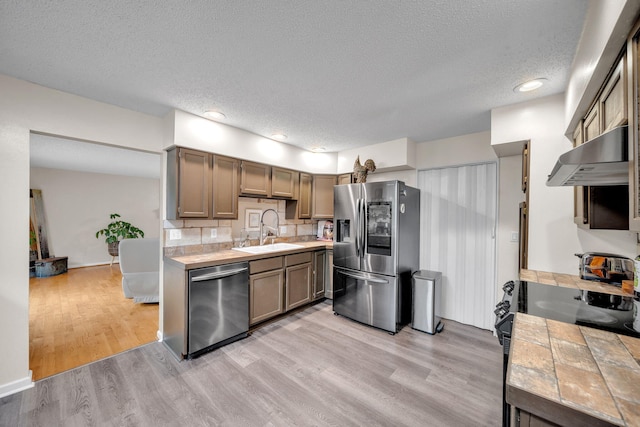 1216 Winding Dr, Sevierville, TN 37876 - kitchen featuring stainless steel appliances, ventilation hood, tile countertops, a textured ceiling, and light wood finished floors
