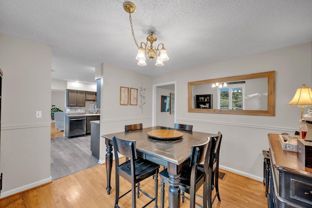 1216 Winding Dr, Sevierville, TN 37876 - dining area with a chandelier, light wood-style flooring, a textured ceiling, and baseboards