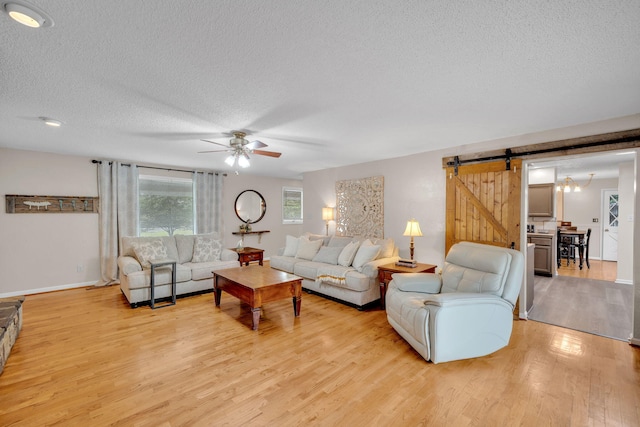 1216 Winding Dr, Sevierville, TN 37876 - living room featuring a barn door, a textured ceiling, light wood-type flooring, ceiling fan, and baseboards