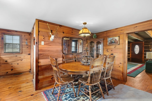 dining space with wooden walls and wood-type flooring