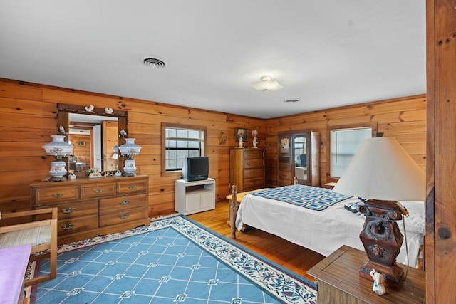 bedroom featuring hardwood / wood-style flooring and wood walls