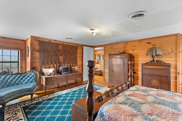 bedroom with wood-type flooring and wooden walls