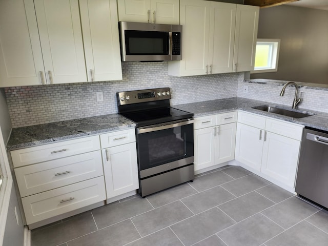 kitchen with appliances with stainless steel finishes, backsplash, white cabinetry, and sink