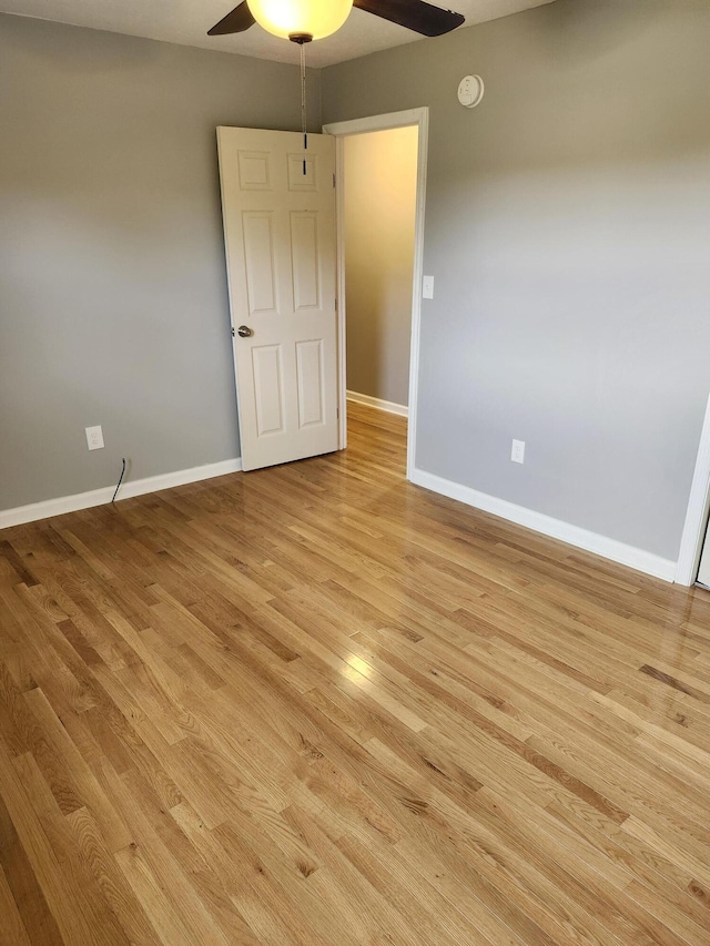 empty room with ceiling fan and light hardwood / wood-style flooring