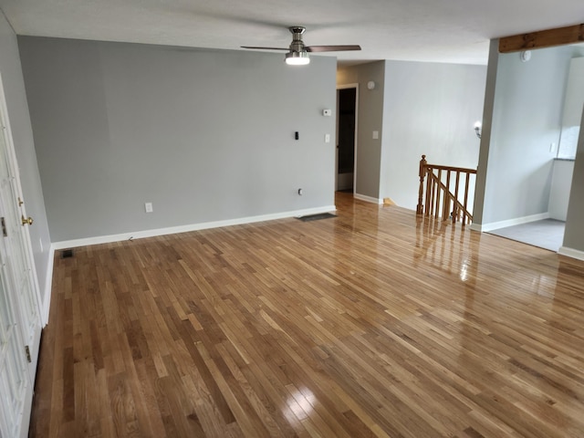 spare room with beamed ceiling, hardwood / wood-style flooring, and ceiling fan