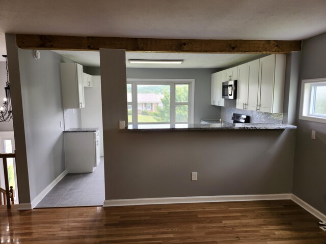 kitchen featuring a healthy amount of sunlight, stone counters, white cabinetry, and stainless steel appliances