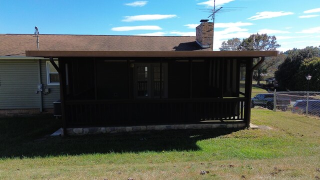 back of house featuring a lawn and a sunroom