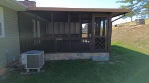 view of property exterior featuring a lawn, a sunroom, and central AC unit