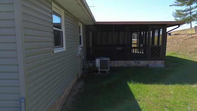 view of side of home featuring a sunroom, central air condition unit, and a lawn