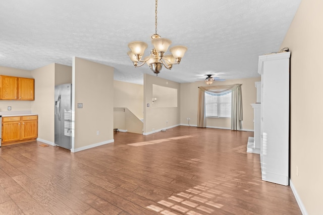 unfurnished living room with ceiling fan with notable chandelier, light hardwood / wood-style flooring, and a textured ceiling