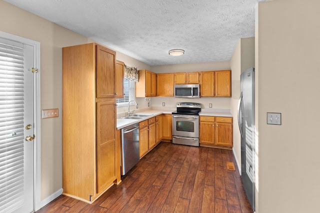 kitchen featuring stainless steel appliances, sink, a textured ceiling, and dark hardwood / wood-style floors