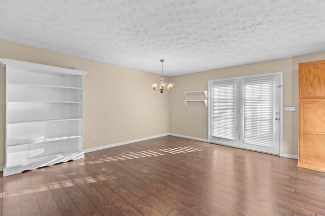 unfurnished room featuring dark hardwood / wood-style flooring, a chandelier, and a textured ceiling