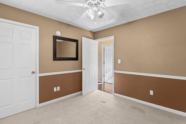 unfurnished room featuring ceiling fan, light carpet, and a textured ceiling