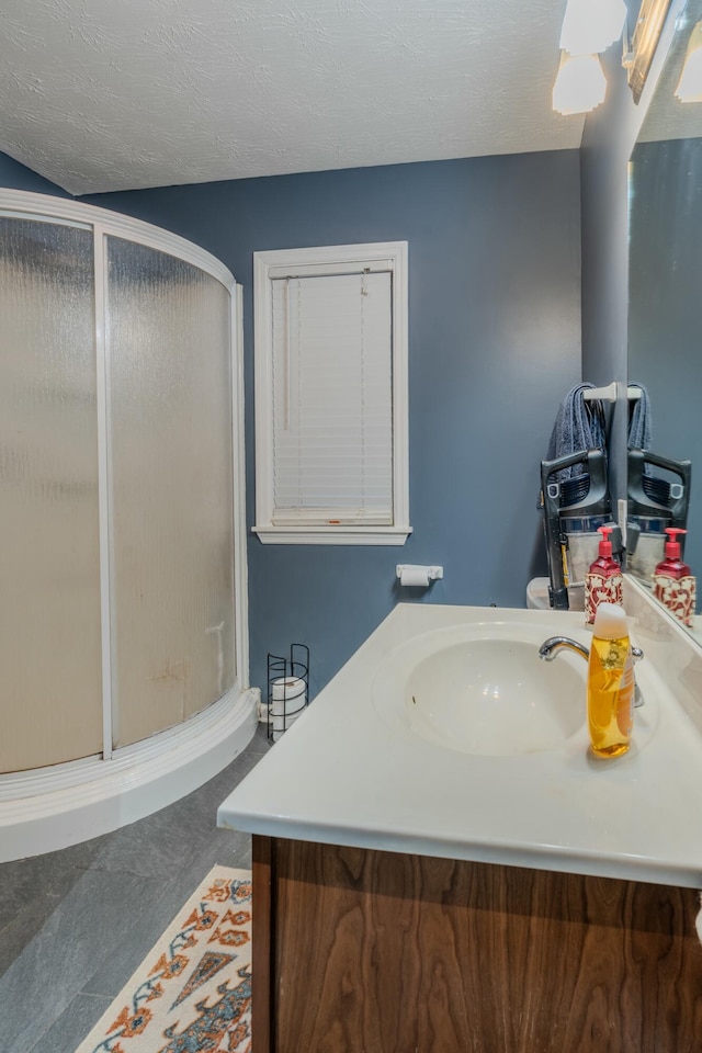 bathroom featuring vanity, a textured ceiling, and a shower with shower door