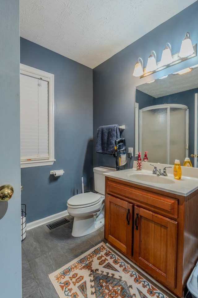 bathroom with a shower with door, tile patterned flooring, vanity, a textured ceiling, and toilet