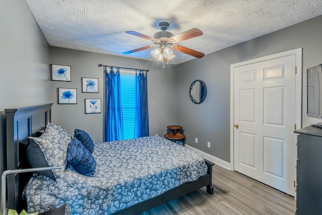 bedroom with ceiling fan, light hardwood / wood-style flooring, and a textured ceiling