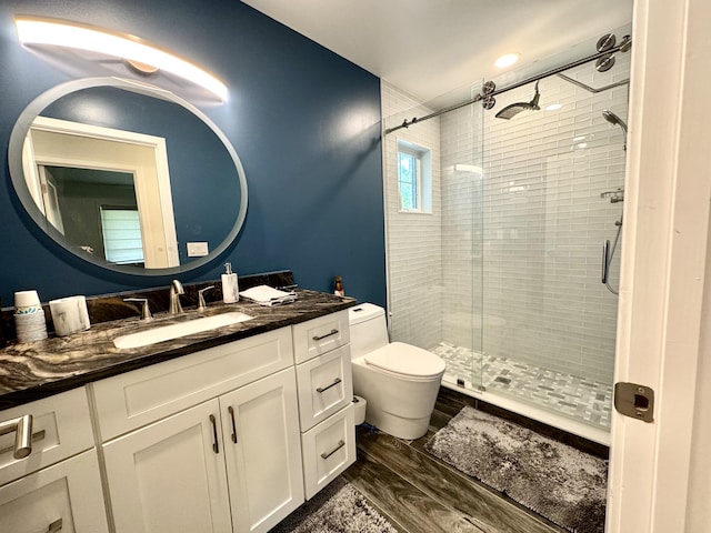 full bath with a shower stall, toilet, wood finished floors, and vanity