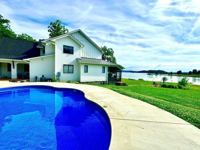 swimming pool with a water view, a lawn, and a patio