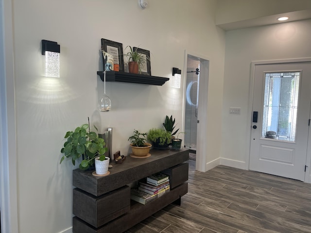 foyer with dark wood-style flooring and baseboards