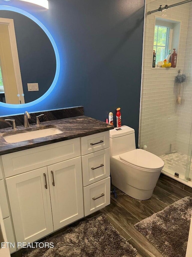 bathroom featuring wood finished floors, a shower stall, toilet, and vanity
