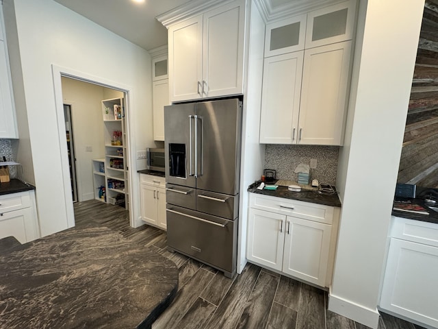 kitchen featuring stainless steel appliances, backsplash, dark countertops, glass insert cabinets, and white cabinetry