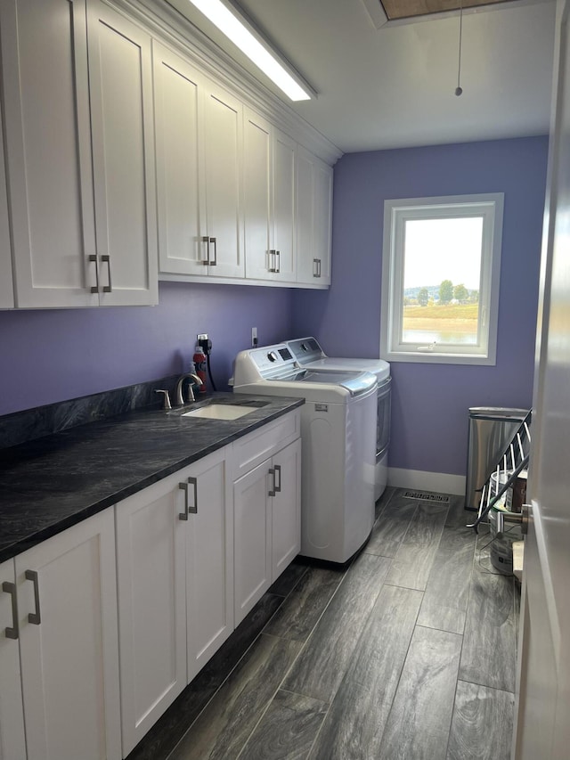 laundry area featuring cabinet space, washer and clothes dryer, baseboards, and wood tiled floors