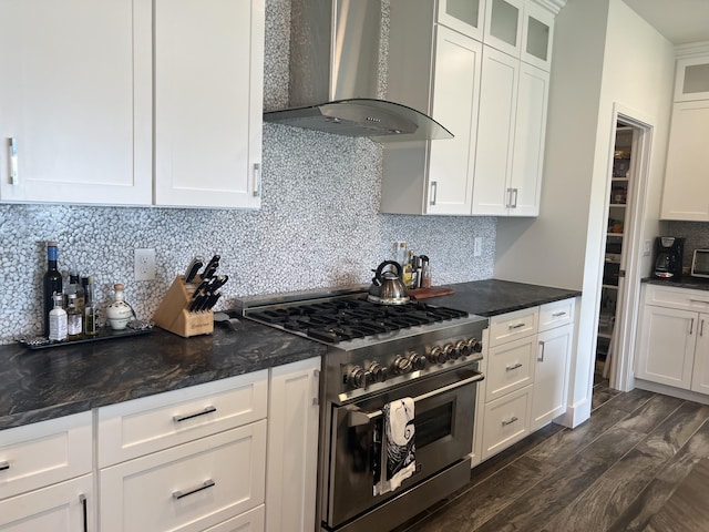 kitchen with wall chimney exhaust hood, high end stainless steel range, tasteful backsplash, glass insert cabinets, and white cabinets