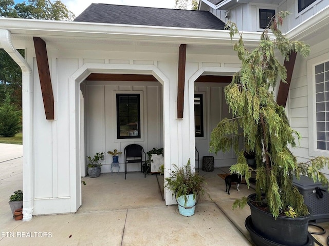 entrance to property with board and batten siding, covered porch, and a shingled roof