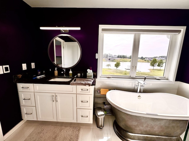 full bath featuring a soaking tub, vanity, tile patterned floors, and a water view