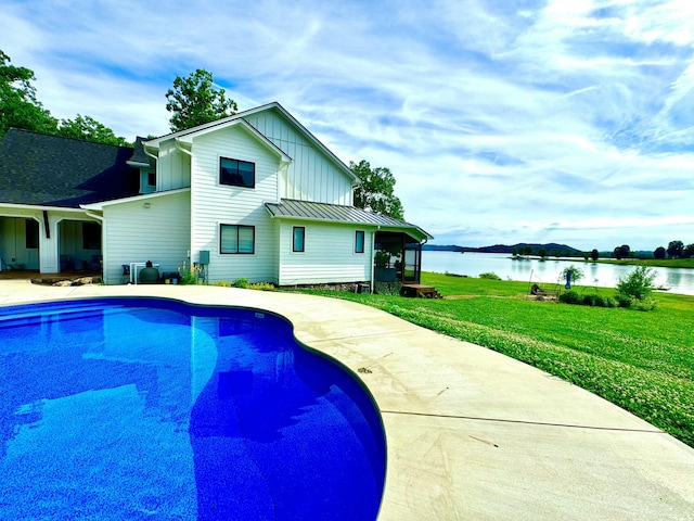 outdoor pool featuring a water view, a yard, and a patio area