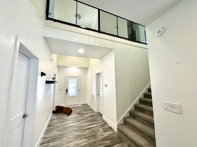 foyer entrance featuring wood finished floors, a towering ceiling, baseboards, and stairs