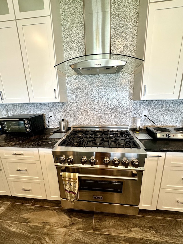 kitchen featuring premium range, wall chimney exhaust hood, black microwave, white cabinetry, and decorative backsplash