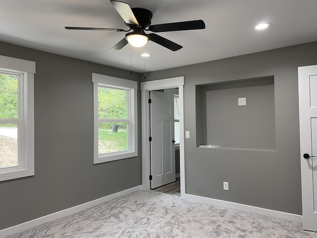 unfurnished bedroom with ceiling fan, light carpet, and multiple windows