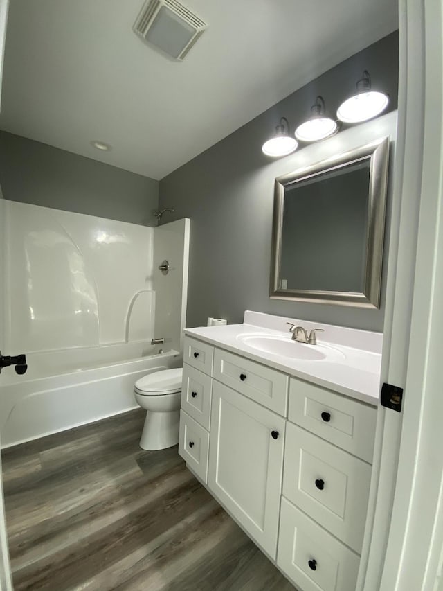 full bathroom featuring hardwood / wood-style floors, vanity, shower / bathtub combination, and toilet